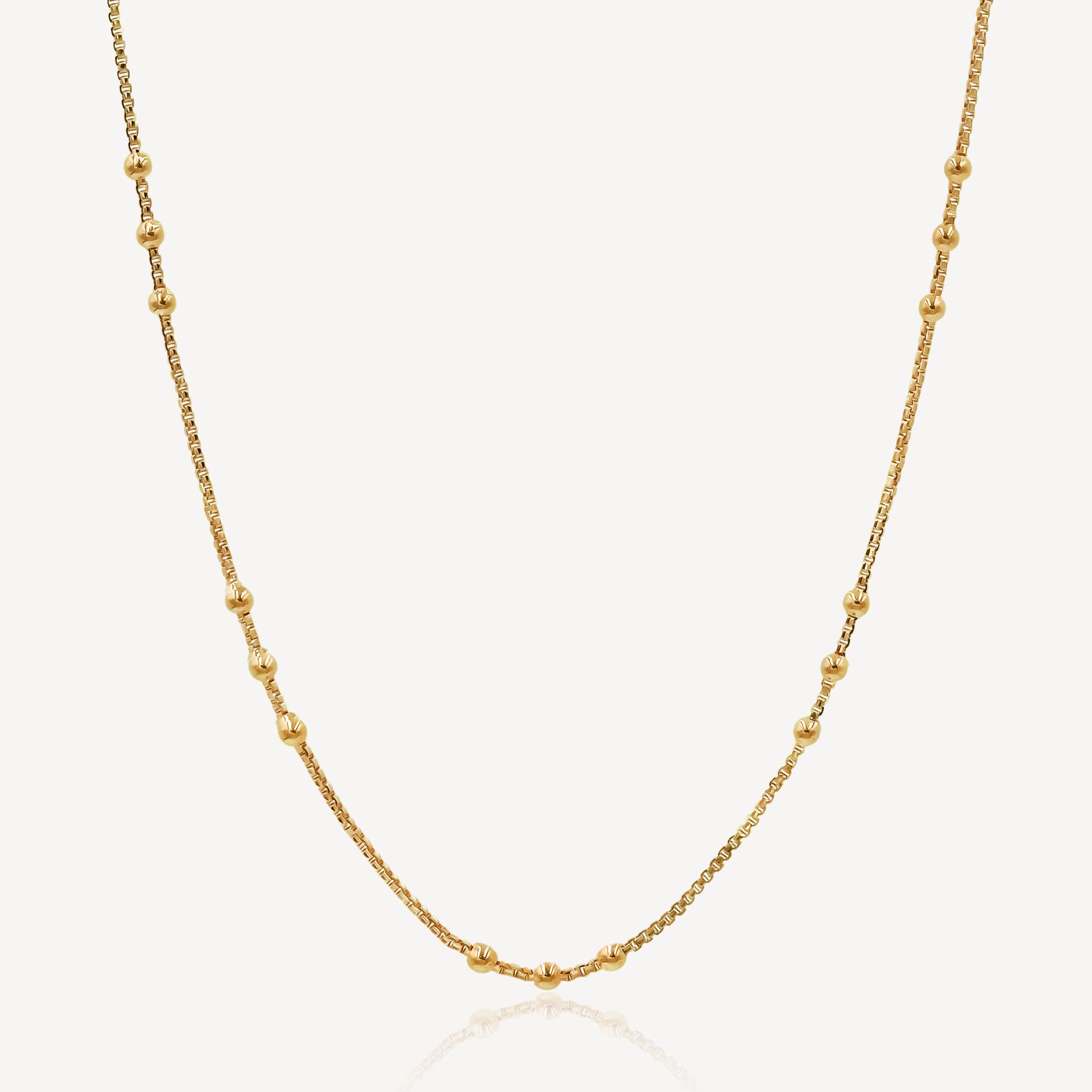 A gold-colored chain necklace with a series of uniform links and small embellishments, displayed against a white background.