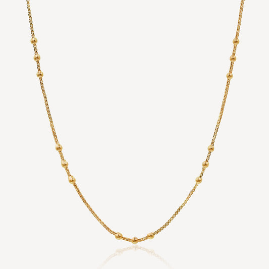 A gold-colored chain necklace with a series of uniform links and small embellishments, displayed against a white background.