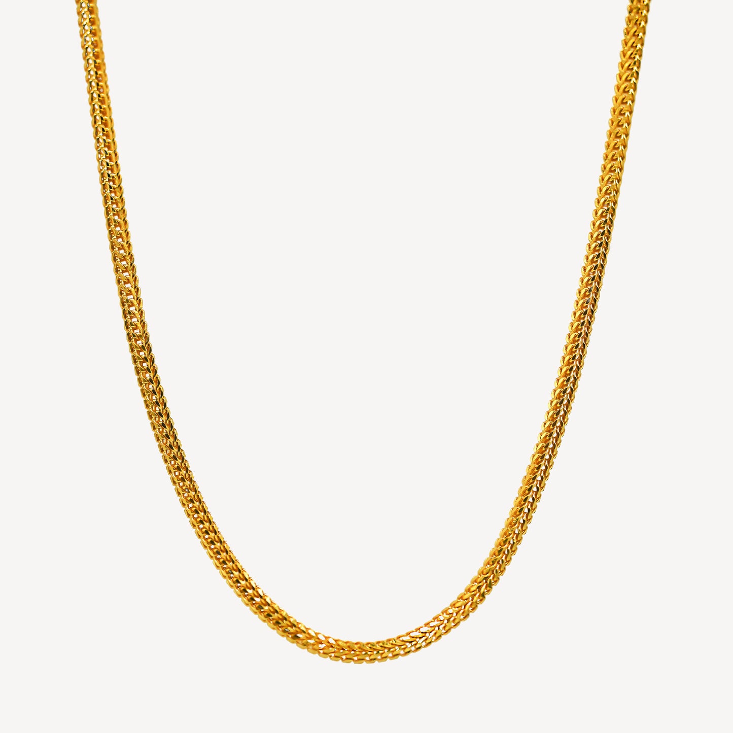 A gold dragon chain necklace laid out on a plain background.